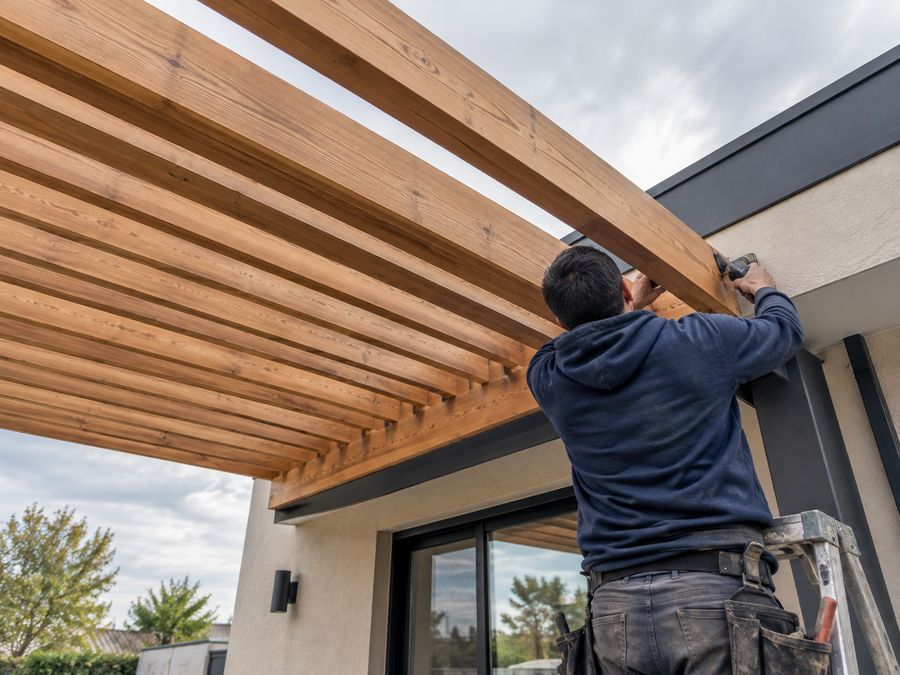 Trabajador con polerón azul marino KALCO armando pérgola de madera